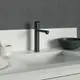 Küchenarmatur in Schwarz von Ideal Standard, mit hohem Auslauf und modernem, minimalistischen Design, montiert auf einer weißen Küchenarbeitsplatte neben Geschirr und Schalen.
